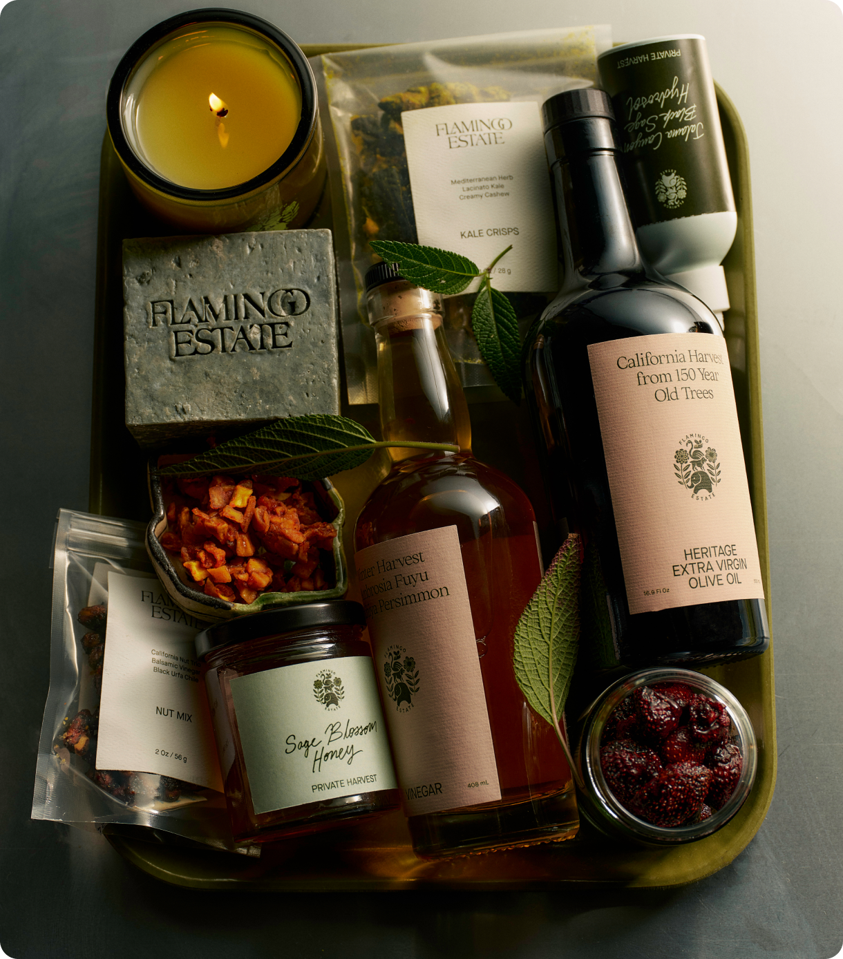 A candle, soap, and various gourmet food items are arranged in a tray.