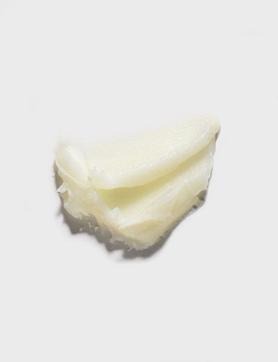 A dollop of creamy, off-white substance sits against a plain grey background.