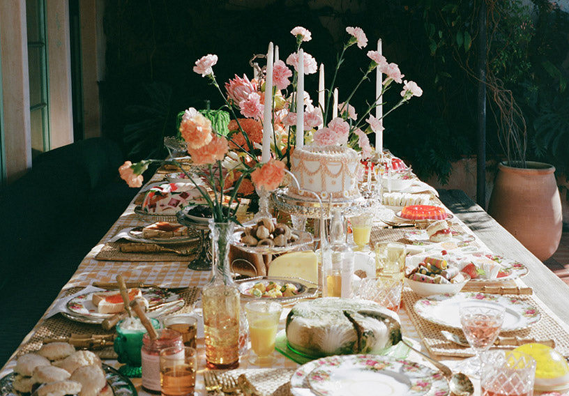 A lavishly set dining table features a decorative cake with candles.