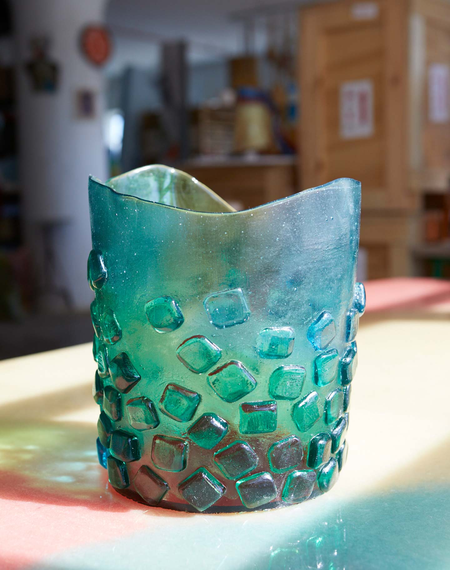 A textured, translucent green vase decorated with raised square shapes.